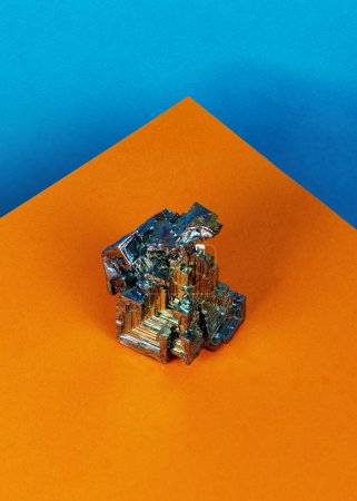 Téléchargez les photos : Un morceau de bismuth avec un fond bleu et orange audacieux et une géométrie minimaliste moderne - en image libre de droit