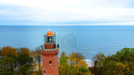 Téléchargez les photos : Photo prise par un drone du phare de Gaski, en Pologne, par une journée nuageuse de novembre. La mer sereine, les vagues douces et la plage vide créent une scène côtière tranquille, offrant une retraite paisible par la Baltique. - en image libre de droit