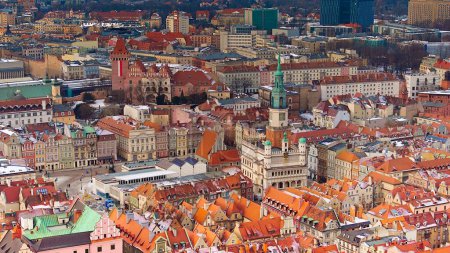 Von oben eingefangen, erstrahlt der alte Marktplatz von Poznan im winterlichen Tageslicht, umgeben von historischen Stadthäusern. Die Drohnenaufnahme zeigt die reiche Architekturgeschichte der Stadt und die heitere Atmosphäre eines Wintertages.