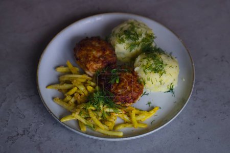 Die klassische polnische Küche: Schweinehack-Burger, Kartoffelpüree, gelbe Wachsbohnen, Semmelbrösel, garniert mit fein gehacktem Dill. 