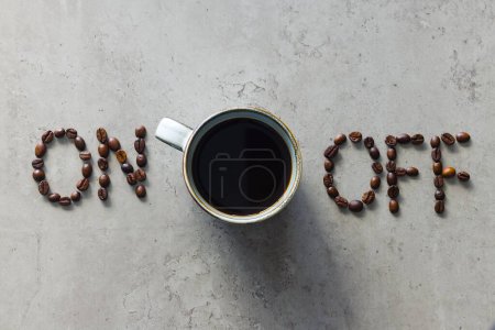 La foto muestra "on" y "off" deletreado con granos de café, con una taza de café negro recién hecho colocado entre ellos. Sirve como metáfora para encender la mente, el cuerpo y el individuo para estimular la acción..