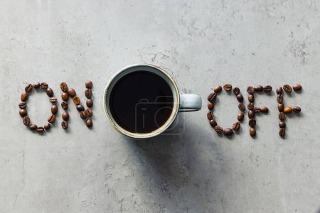 La foto muestra "on" y "off" deletreado con granos de café, con una taza de café negro recién hecho colocado entre ellos. Sirve como metáfora para encender la mente, el cuerpo y el individuo para estimular la acción..