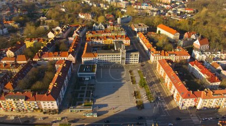 A drone shot captures Koszalin city center bathed in golden light, featuring the cathedral, Victory Street, and town hall.