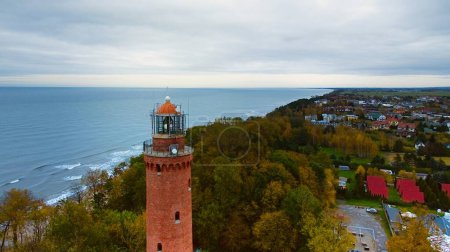 Drohnenaufnahme des Gaski Leuchtturms, Polen, an einem bewölkten Novembertag. Das ruhige Meer, sanfte Wellen und ein leerer Strand schaffen eine ruhige Küstenlandschaft, die einen friedlichen Rückzugsort an der Ostsee bietet. 