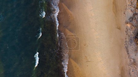 Golden hour aerial: Sandy beach, gently rolling waves