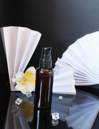 Téléchargez les photos : Flacon compte-gouttes cosmétique verre-ambre avec capuchon noir et fleurs - en image libre de droit