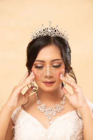 Photo for Makeup woman pose sitting formal relaxed cheerful looking sideways up the stairs holding cheeks closing eyes wearing beautiful dress indoor photo shot closeup. single wedding national bride studio - Royalty Free Image
