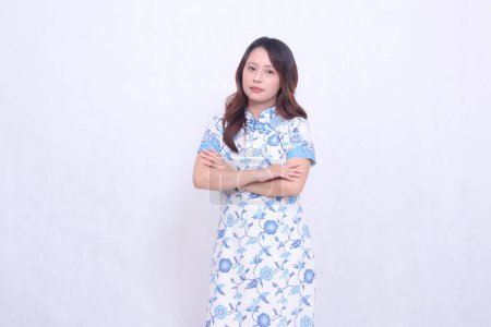 Photo for Beautiful indonesian girl smile wearing modern chinese dress arms crossed isolated on white background. happy Chinese New Year - Royalty Free Image