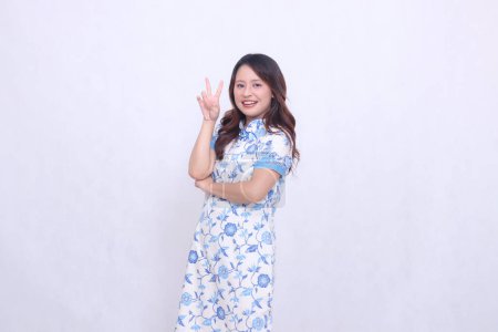 Photo for Beautiful asian woman smiling crookedly wearing modern chinese dress right hand marked 2 dua or peace isolated on white background. happy Chinese New Year - Royalty Free Image
