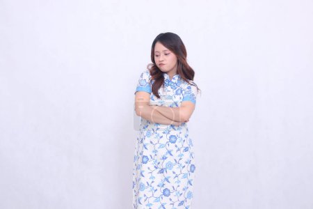 beautiful pouting Javanese Chinese woman wearing a modern Chinese dress with arms crossed on a white background. happy Chinese New Year