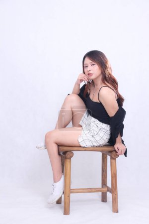 corps plein belle asiatique femme 20s bureau formel élégant sexy sourire gai assis mains sensuelles tenant les joues sur chaise en bois isolé fond blanc