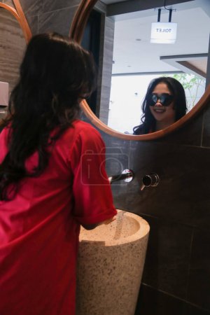 Photo for Beauty of young asian woman in glasses smile standing in front of glass and sink aesthetic washing hands for health, fashion, science, knowledge content - Royalty Free Image