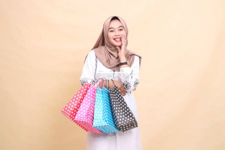 La historia de una joven musulmana asiática con un hiyab le gusta hacer anuncios mirando a la cámara y llevando bolsas de compras. para publicidad, cultura, Eid y Ramadán