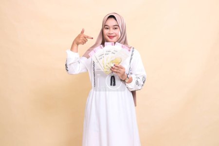 retrato de una hermosa chica musulmana asiática que lleva un hiyab con una sonrisa elegante que muestra regalos y regalos en Eid. utilizado para la publicidad, regalos, Eid y Ramadán