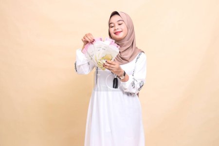 Porträt einer schönen asiatischen Muslimin, die einen Hijab trägt, lächelt, Geschenke und Geschenke am Eid hält und zählt. verwendet für Werbung, Werbegeschenke, Eid und Ramadan