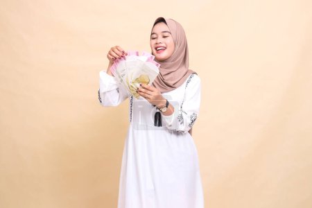 Portrait of a beautiful Asian Muslim girl wearing a happy hijab holding her hands up and counting gifts and gifts on Eid. used for advertising, giveaways, Eid and Ramadan