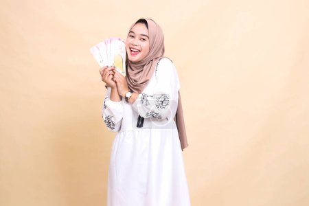 portrait of a beautiful Asian Muslim woman wearing a hijab happy to hold and show off gifts and gifts to the right on Eid. used for advertising, giveaways, Eid and Ramadan
