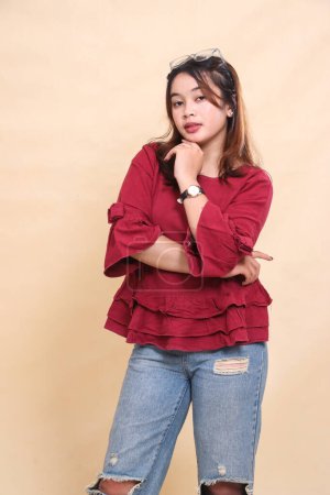Beautiful elegant Asian woman in red shirt, flat smile, arms crossed and chin looking at the camera. used for fashion, advertising and industrial content