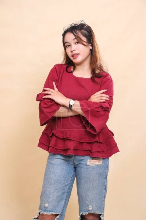 Belle femme asiatique élégante en chemise rouge souriant avec les bras croisés en regardant la caméra. utilisé pour la mode, la publicité et le contenu industriel
