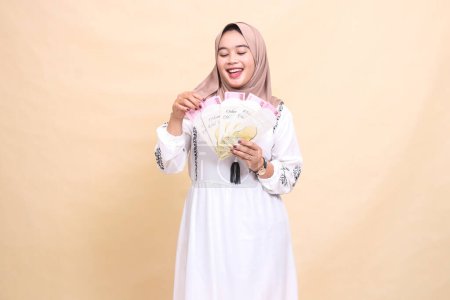 retrato de una hermosa mujer musulmana asiática con un hiyab felizmente sosteniendo y contando regalos ampau fitrah en Eid. utilizado para la publicidad, regalos, Eid y Ramadán