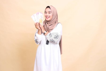 Porträt einer schönen indonesischen Muslimin, die am Eid einen fröhlichen Hijab trägt und Geschenke und Geschenke nach rechts hält. verwendet für Werbung, Werbegeschenke, Eid und Ramadan