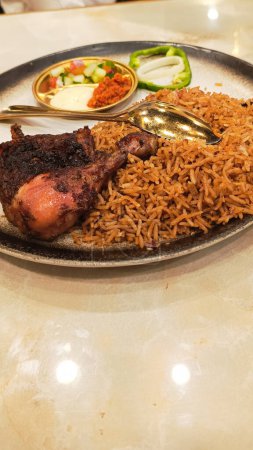 retrato de nasi kebuli ayam (arroz kebuli de pollo) en el centro con encurtidos, salsa y cuchara, comida árabe típica hecha en Indonesia ubicada en el primer plano de la mesa