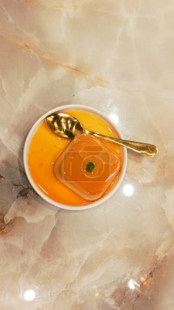 Porträt von Orangenpudding auf einem Teller und Löffel mit Leerraum auf beiden Seiten