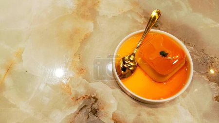 Orangefarbener Pudding auf Teller und Löffel mit Leerraum daneben