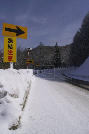 Téléchargez les photos : Route enneigée dans la montagne au Japon et panneau routier. - en image libre de droit