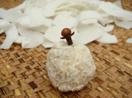 A handmade coconut ball with a clove in the center,and  dried coconut slices.