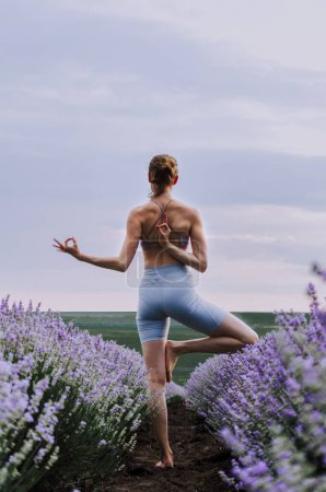 Photo for Woman practicing yoga in lavender field - Royalty Free Image