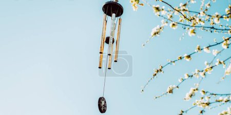 Photo for Wind chime with zen symbolism hanging on tree in blossom with copy space - Royalty Free Image