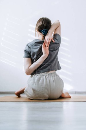 Frau in lässiger Kleidung praktiziert Yoga zu Hause