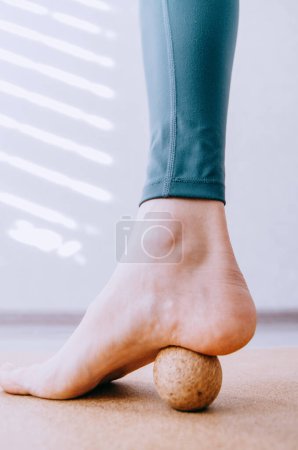 Primer plano del pie haciendo ejercicio de fascia plantar MFR con bola de masaje de corcho