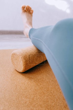 Téléchargez les photos : Gros plan de la femme faisant massage MFR de la jambe inférieure sur un rouleau de liège - en image libre de droit
