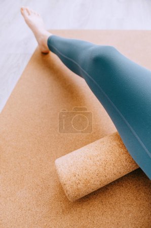 Close up of woman doing hamstrings MFR massage on a cork roller