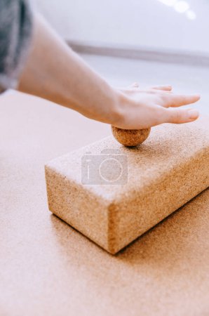 Close up of hand doing palm fascia release exercise with cork ball on cork block
