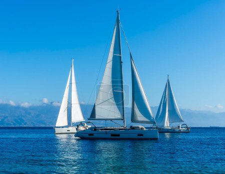 Téléchargez les photos : Voiliers avec voiles blanches en mer bleue, paysage marin de beaux bateaux dans le golfe de mer avec côte de montagne en arrière-plan - en image libre de droit
