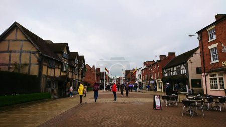 Photo for Stratford-upon-Avon, United Kingdom - April 28, 2018: street with people walking and Shakespeares Birthplace at the side under a cloudy sky - Royalty Free Image