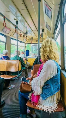 Photo for Vienna, Austria - 06.07.2018: Interior of a tram with passengers sitting in a sunny day - Royalty Free Image