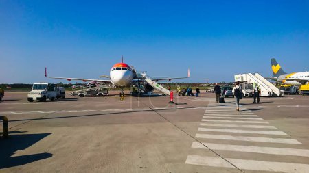 Photo for Berlin Brandenburg Airport, Berlin, Germany - 04.18.2018: Passengers boarding the aircraft through a staircase under a bright blue sky - Royalty Free Image