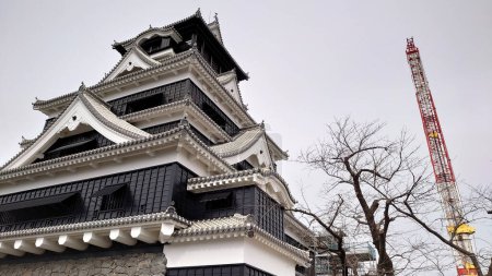 Téléchargez les photos : Kumamoto, Japon - 01.26.2020 : Gros plan sur le château de Kumamoto en cours de reconstruction après le tremblement de terre de 2016 avec des échafaudages et une grue en vue sous un ciel nuageux - en image libre de droit