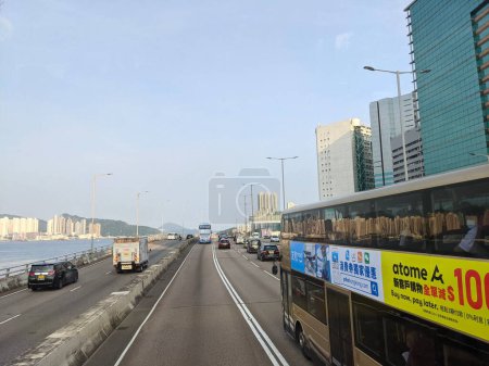 Foto de Hong Kong - 09.13.2021: Ocupada escena con coches, autobuses y camiones en el corredor este de la isla a las afueras de North Point en la isla de Hong Kong bajo la luz del sol durante la pandemia, vista desde un autobús de dos pisos - Imagen libre de derechos