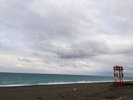 Photo for Hualien, Taiwan - 11.26.2022: A red and white metal structure with warning horns standing on the empty Qixingtan Beach facing the wavy Pacific Ocean on a stormy day under clouds during the pandemic - Royalty Free Image