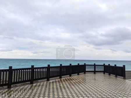 Photo for Hualien, Taiwan - 11.26.2022: An empty observation deck with railings and square tile floor facing Qixingtan Beach and Pacific Ocean on a storm day under clouds during the pandemic - Royalty Free Image