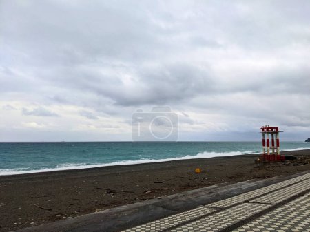 Foto de Hualien, Taiwán - 11.26.2022: Una estructura metálica roja y blanca con cuernos de advertencia en la vacía playa de Qixingtan junto a escalones de baldosas frente al Océano Pacífico en un día tormentoso durante la pandemia - Imagen libre de derechos