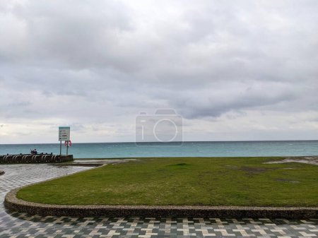 Photo for Hualien, Taiwan - 11.26.2022: Tourists taking selfies in a public park with a lawn and cycle parking spaces in front of Qixingtan Beach on a stormy day under clouds during the pandemic - Royalty Free Image