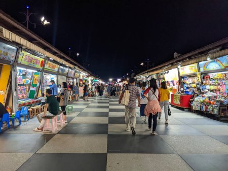 Photo for Hualien, Taiwan - 11.27.2022: Customers browsing the toys and gaming market stalls with children playing street games in Dongdamen Night Market in Hualien during the pandemic at night - Royalty Free Image