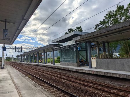 Photo for Hualien, Taiwan - 11.28.2022: An empty platform in Fuli Railway Station with a worker working on the opposite platform under a cloudy sky during the pandemic - Royalty Free Image