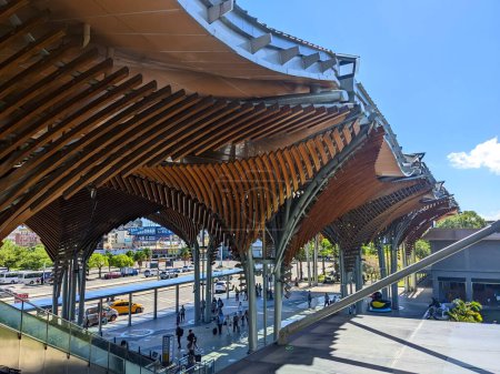 Photo for Hualien, Taiwan - 11.28.2022: Hualien Railway Station with curved wooden ceiling while passengers getting off cars and walking to enter the station via escalator during the pandemic on a sunny day - Royalty Free Image